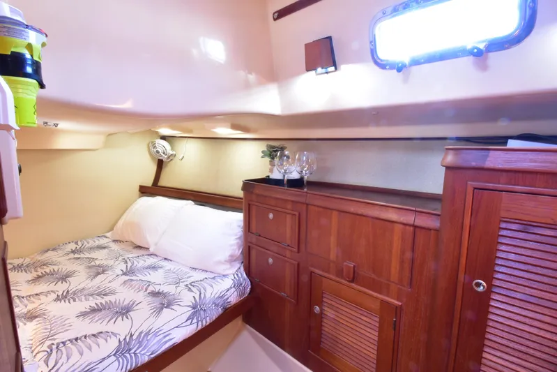 Aftia Yacht Photos Pics Cozy cabin interior of 1999 Island Packet 380 sailboat with bed and wooden storage.