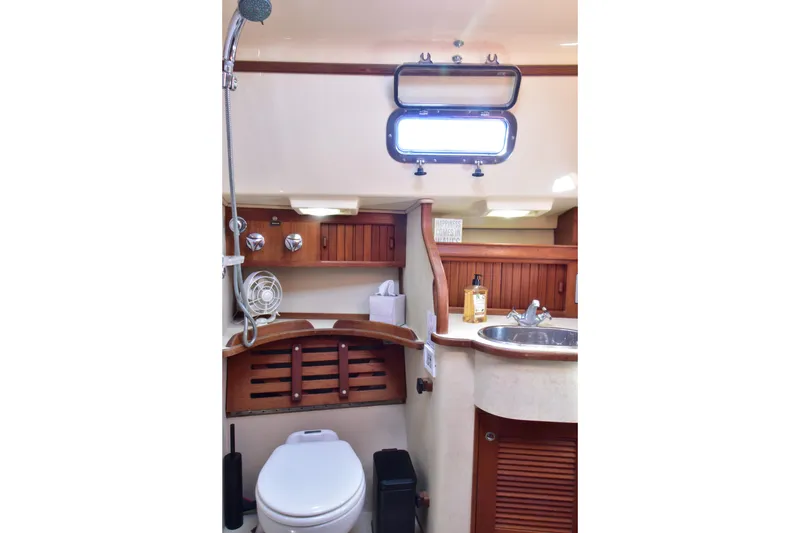 Aftia Yacht Photos Pics 1999 Island Packet 380 yacht bathroom with sink, toilet, and wooden cabinetry.