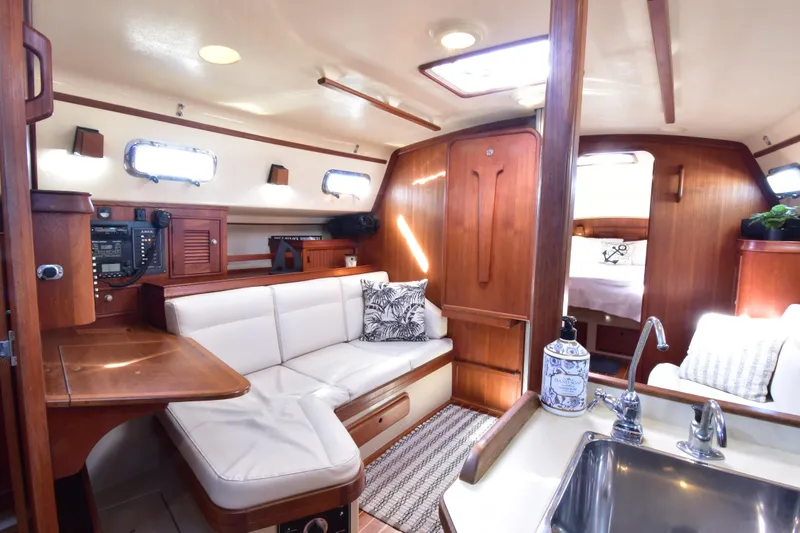 Aftia Yacht Photos Pics Interior of 1999 Island Packet 380 sailboat with cozy seating and wooden finishes.