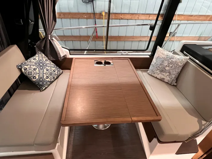  Yacht Photos Pics Interior seating area of 2021 Jeanneau NC 1095 FLY with wooden table and cushions.