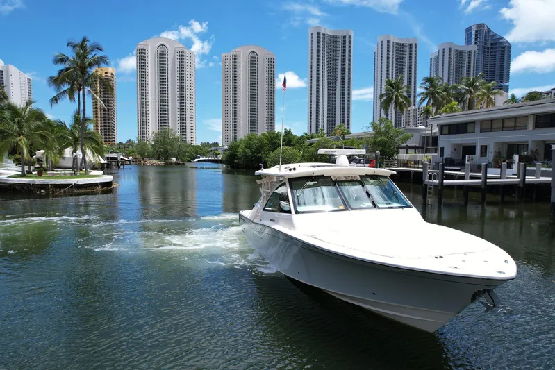37 Grady White Freedom Yacht Photos Pics 2017 Grady-White Freedom 375 boat cruising in a city canal with skyscrapers and palm trees.