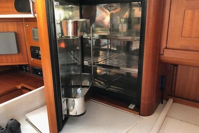 Dark N' Stormy III Yacht Photos Pics Interior of 1999 Sweden Yachts 45, featuring a compact kitchen fridge with wooden cabinetry.