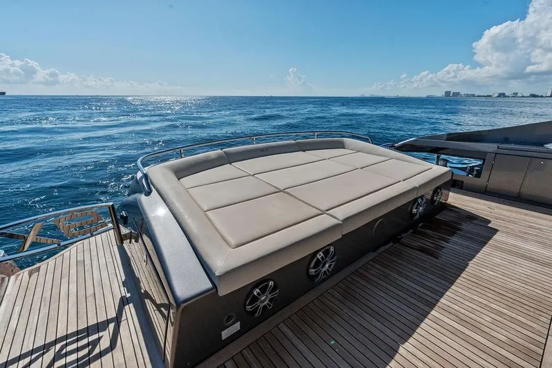 One Spin 3 Yacht Photos Pics 2019 Pershing 9X yacht deck with sunbed, overlooking the ocean under a clear blue sky.