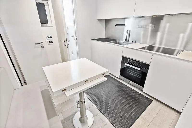 One Spin 3 Yacht Photos Pics Modern kitchen interior on 2019 Pershing 9X yacht, featuring sleek white cabinetry and appliances.