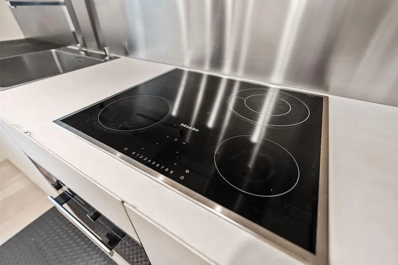 One Spin 3 Yacht Photos Pics Modern kitchen with sleek Miele induction cooktop on Pershing 9X yacht, 2019 model.