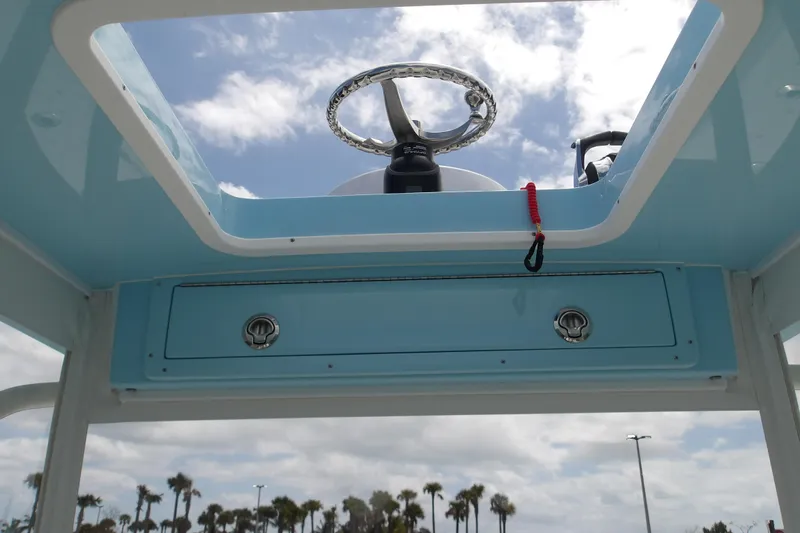  Yacht Photos Pics 2022 SeaVee 370z boat helm with blue console and steering wheel under a cloudy sky.