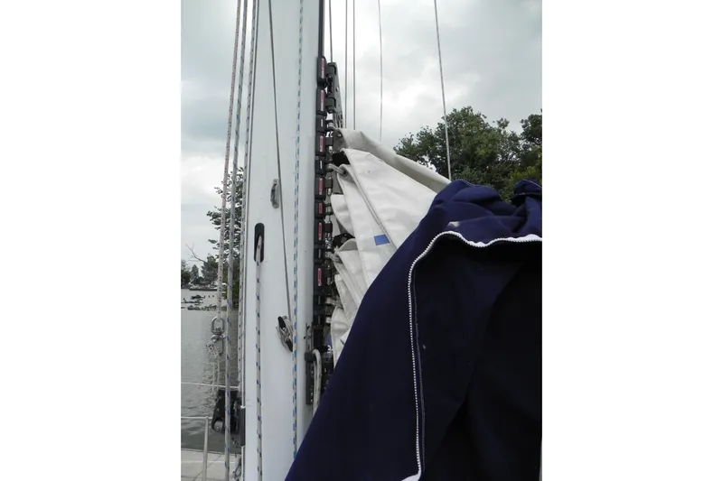 Cricket Yacht Photos Pics 1988 Tartan 40 sailboat mast with rigging and sails, docked near trees.