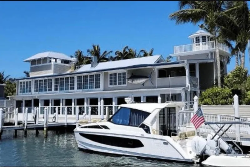  Yacht Photos Pics Aquila 36 Cruiser 2022 docked by a waterfront house with palm trees.