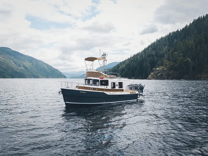 Ambraden Yacht Photos Pics 2022 Ranger Tugs R-31 CB cruising on a scenic lake surrounded by forested hills.