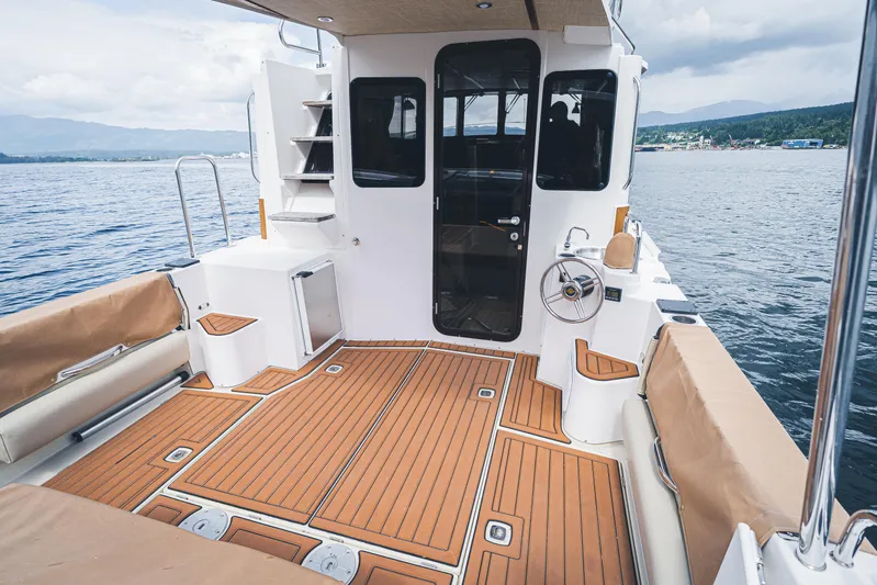 Ambraden Yacht Photos Pics 2022 Ranger Tugs R-31 CB boat deck with teak flooring and seating, on calm water.