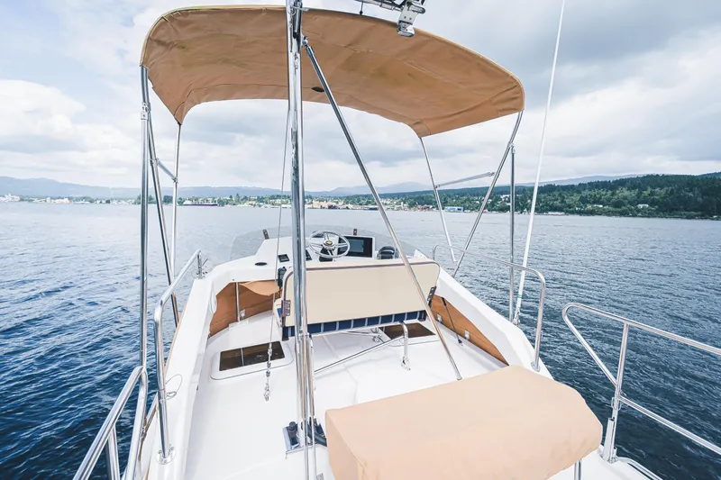 Ambraden Yacht Photos Pics 2022 Ranger Tugs R-31 CB boat with canopy on calm water, scenic background.
