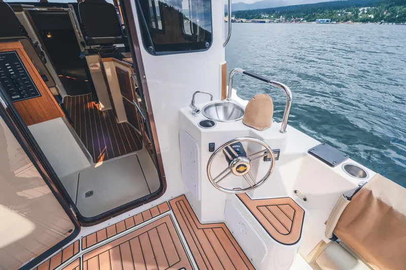 Ambraden Yacht Photos Pics 2022 Ranger Tugs R-31 CB boat interior with helm, sink, and wood flooring.