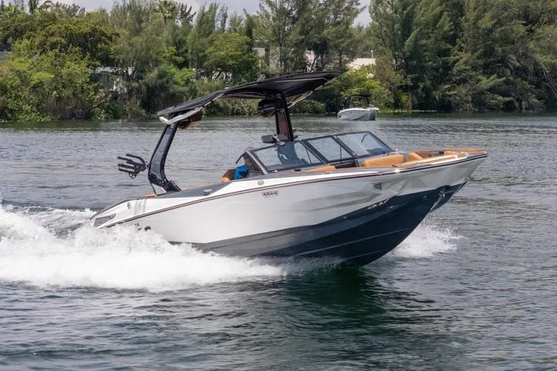  Yacht Photos Pics 2025 Centurion Nv233 boat cruising on a scenic lake with lush greenery.