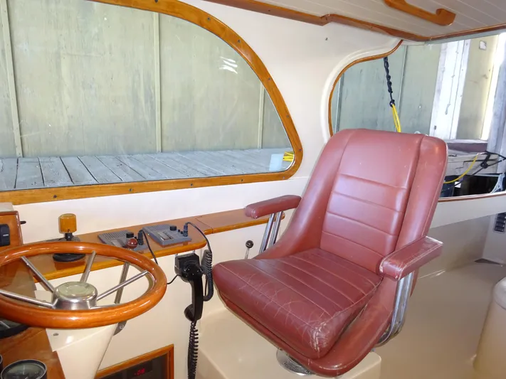 Blue Moon Yacht Photos Pics Interior of a 1995 Hinckley Picnic Boat Classic with leather captain's chair and wooden steering wheel.