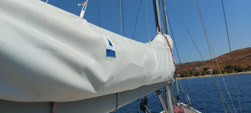  Yacht Photos Pics Sailboat Hanse 461 (2006) with covered mainsail, sailing near a coastal landscape.