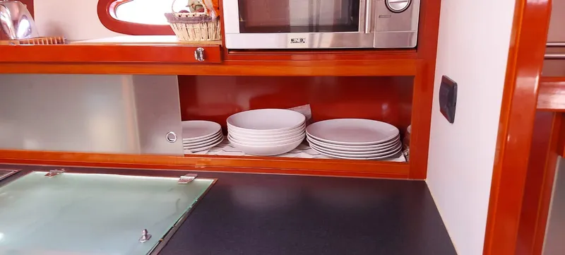  Yacht Photos Pics Modern yacht kitchen with stacked white plates, microwave, and sleek cabinetry on a 2006 Hanse 461.