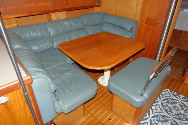 Ale Er Ron Yacht Photos Pics Interior of 2000 Hunter 460 yacht with wooden table and blue cushioned seating.