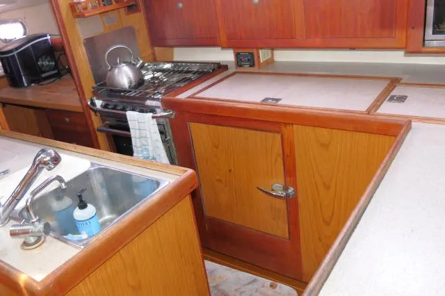 Ale Er Ron Yacht Photos Pics Galley kitchen in 2000 Hunter 460 sailboat with wooden cabinetry and stainless steel sink.