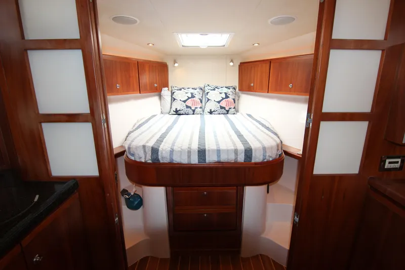 Bloody Knuckles Yacht Photos Pics 2008 Bertram 360 cabin interior with bed, wooden cabinets, and striped bedding.