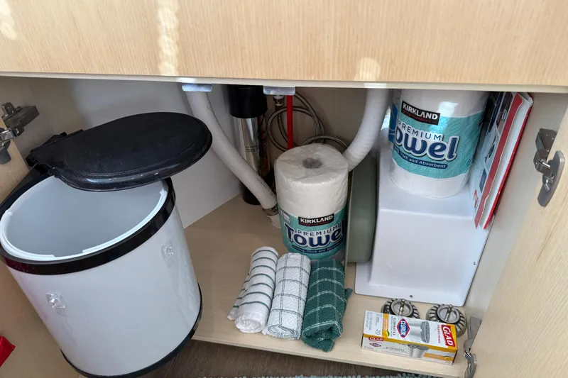 Dauntless Yacht Photos Pics Under-sink storage in 2024 Seawind 1370 yacht with paper towels and cleaning supplies.