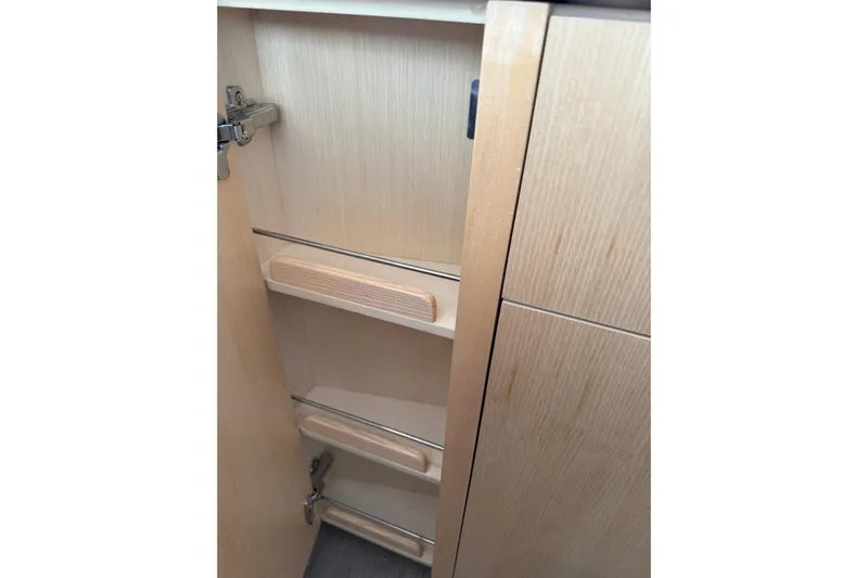 Dauntless Yacht Photos Pics 2024 Seawind 1370 interior cabinet with wooden shelves and metal hinges.