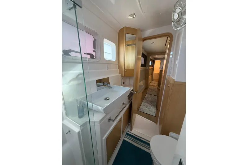 Dauntless Yacht Photos Pics 2024 Seawind 1370 yacht bathroom with modern sink, wooden accents, and glass shower.