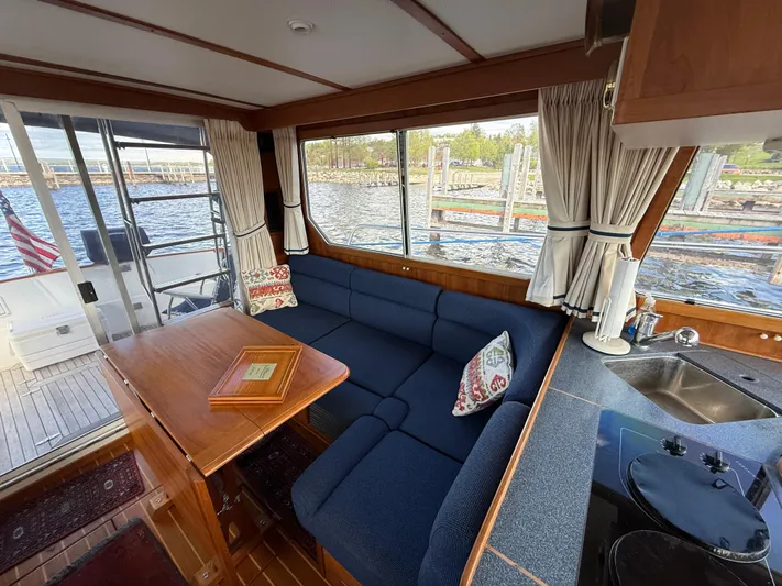  Yacht Photos Pics Interior of 1999 Sabreline 34 Flybridge with blue seating, wooden table, and waterfront view.