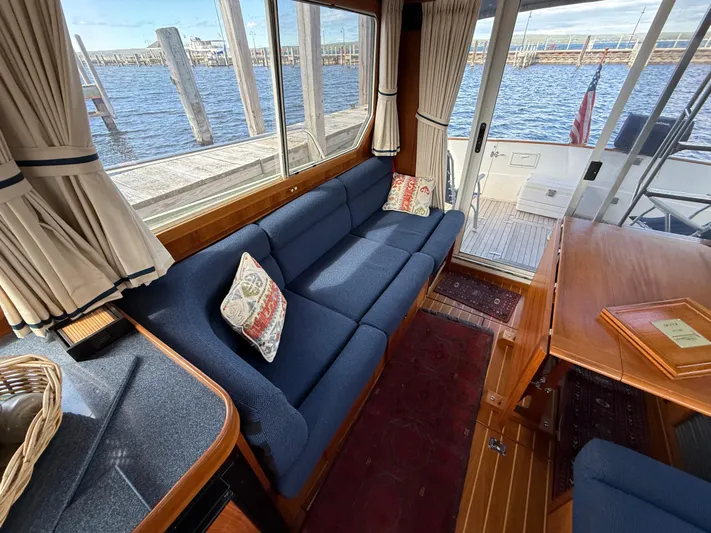  Yacht Photos Pics Interior of 1999 Sabreline 34 Flybridge with blue sofa, wooden table, and waterfront view.