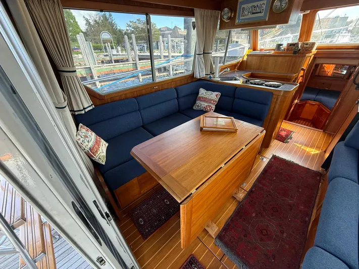  Yacht Photos Pics Interior of 1999 Sabreline 34 Flybridge yacht with blue seating and wooden table.