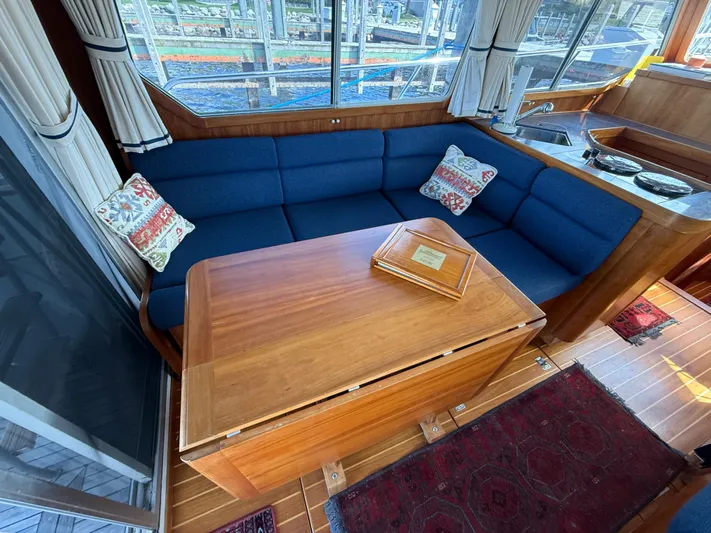 Yacht Photos Pics 1999 Sabreline 34 Flybridge interior with blue seating, wooden table, and decorative pillows.