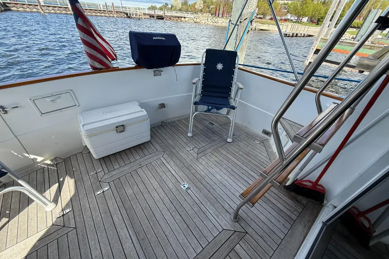 Yacht Photos Pics 1999 Sabreline 34 Flybridge deck with chair, cooler, and American flag by the water.