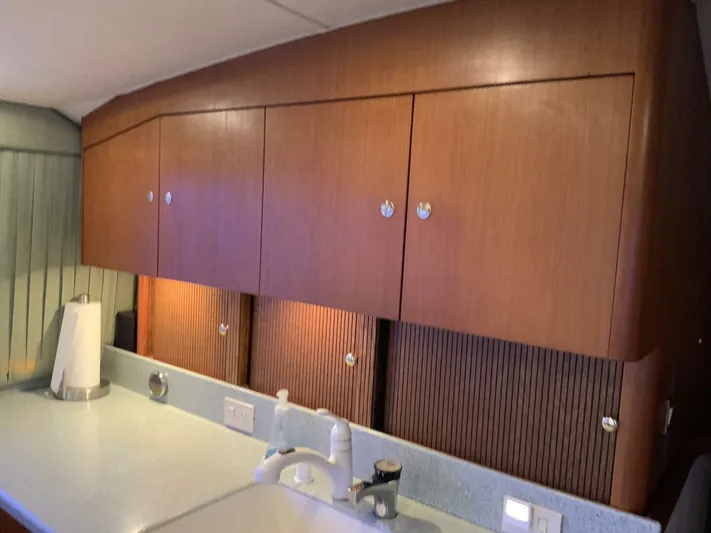 Bona Vida Yacht Photos Pics Interior of 1997 Ocean Yachts 48 Convertible, featuring wooden cabinets and a countertop sink.