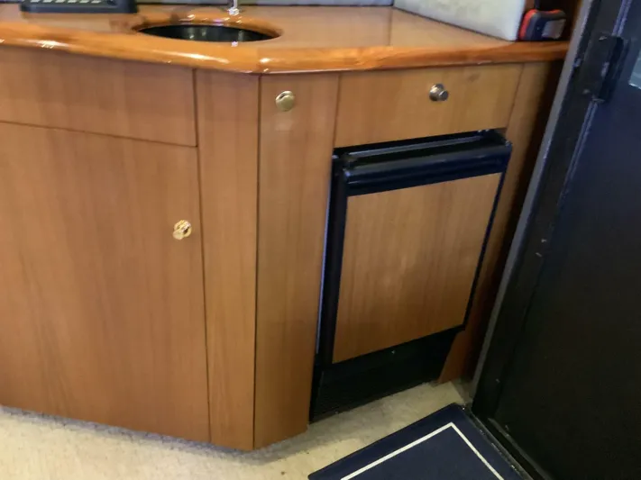 Bona Vida Yacht Photos Pics 1997 Ocean Yachts 48 Convertible yacht interior with wooden cabinetry and compact fridge.