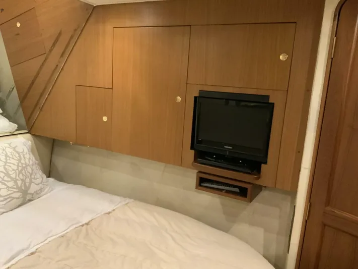 Bona Vida Yacht Photos Pics Bedroom interior of 1997 Ocean Yachts 48 Convertible with TV and wooden cabinetry.