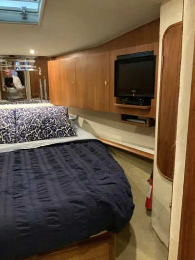 Bona Vida Yacht Photos Pics Interior of 1997 Ocean Yachts 48 Convertible with bed, TV, and wooden cabinetry.