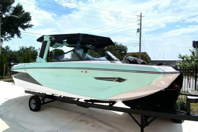  Yacht Photos Pics 2024 Nautique Super Air Nautique G23 boat on trailer, mint green exterior, sunny day.