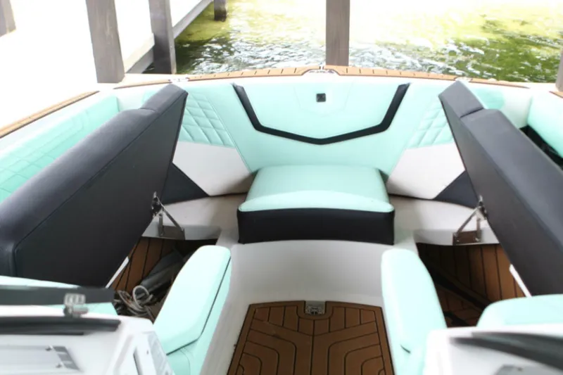  Yacht Photos Pics 2024 Nautique Super Air Nautique G23 interior with mint and black seating, docked by water.