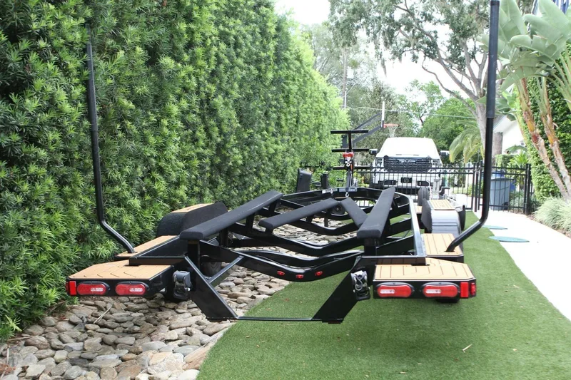  Yacht Photos Pics 2024 Nautique Super Air Nautique G23 boat trailer parked on a lush green driveway.