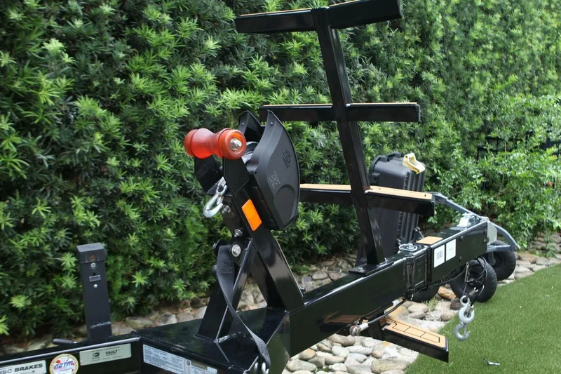  Yacht Photos Pics Trailer hitch for 2024 Nautique Super Air Nautique G23, surrounded by lush greenery.