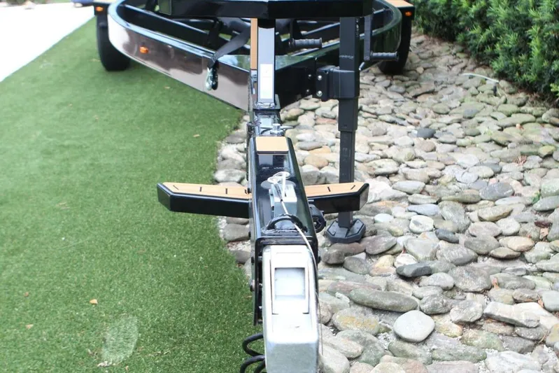  Yacht Photos Pics Trailer hitch of 2024 Nautique Super Air Nautique G23 on grass and stone path.