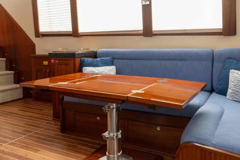 Take 2 Yacht Photos Pics Interior of 2015 Nordic Tug 44 with wooden table and blue seating.
