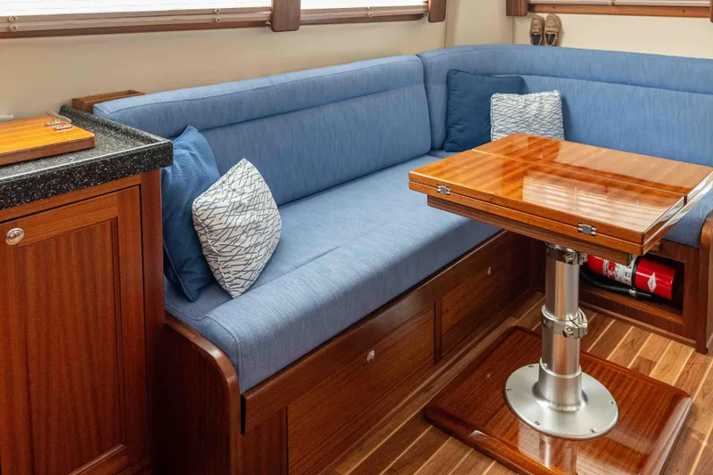 Take 2 Yacht Photos Pics Interior of 2015 Nordic Tug 44 with blue seating and wooden table.