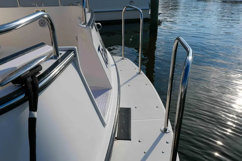 Take 2 Yacht Photos Pics Nordic Tug 44 (2015) boat deck with railing, docked on calm water.