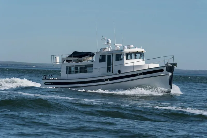 Take 2 Yacht Photos Pics 2015 Nordic Tug 44 cruising on open water, showcasing its sleek design and sturdy build.