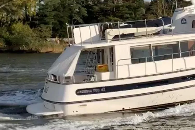 Take 2 Yacht Photos Pics Nordic Tug 44 boat cruising on a river, 2015 model, surrounded by lush greenery.