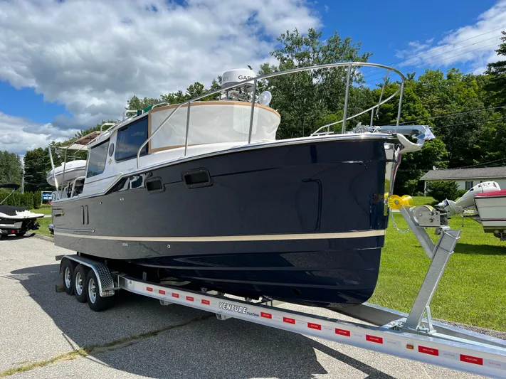  Yacht Photos Pics 2024 Ranger Tugs R-27 boat on trailer, parked outdoors under a partly cloudy sky.