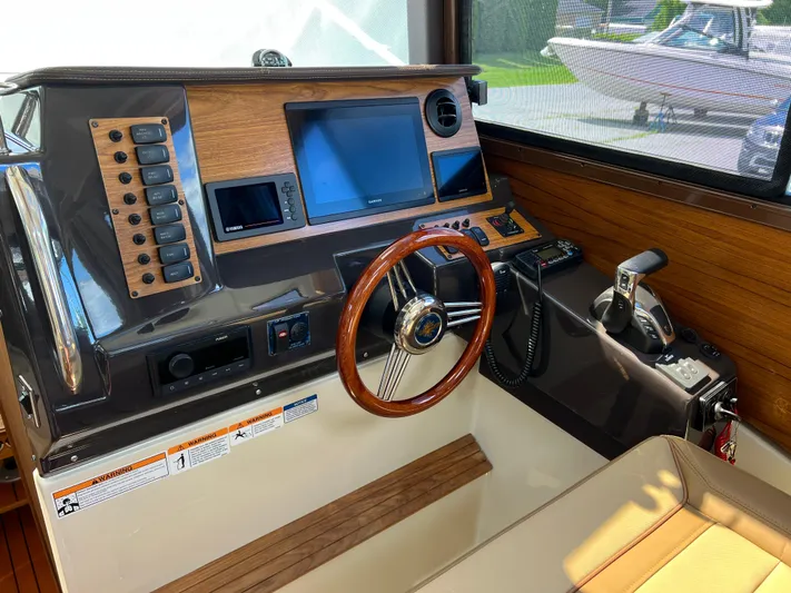  Yacht Photos Pics 2024 Ranger Tugs R-27 helm with wood accents and modern navigation controls.