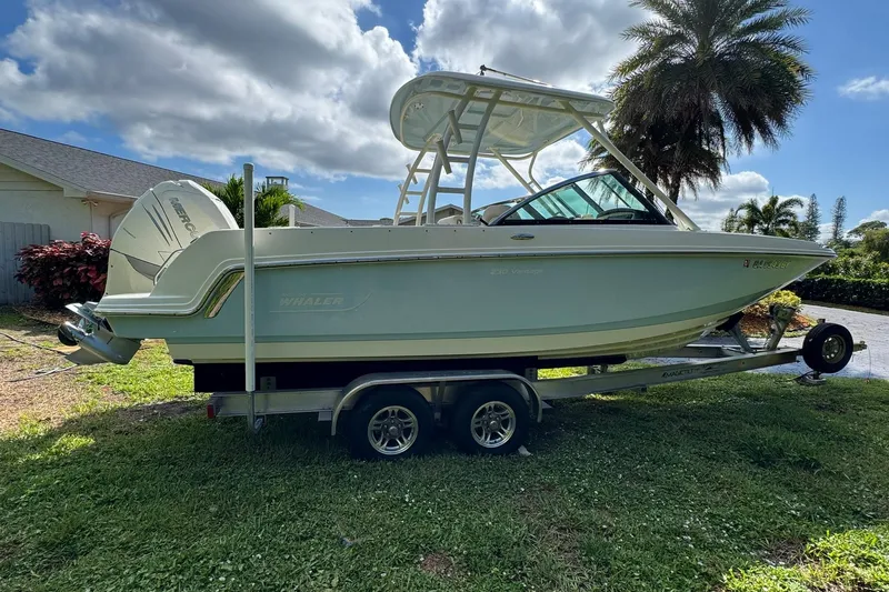  Yacht Photos Pics 2019 Boston Whaler 230 Vantage boat on trailer, parked outdoors under a cloudy sky.