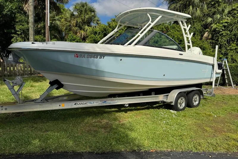  Yacht Photos Pics 2019 Boston Whaler 230 Vantage boat on trailer, parked on grass.