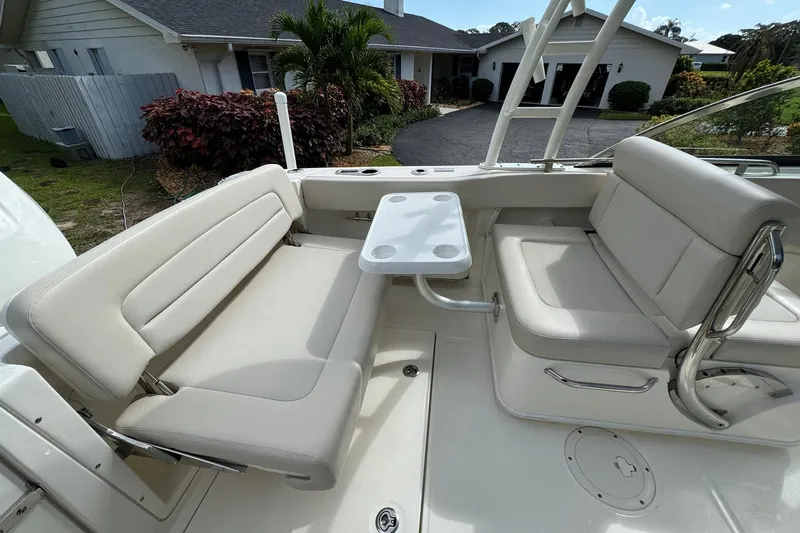  Yacht Photos Pics 2019 Boston Whaler 230 Vantage boat interior with seating and table, parked near a house.